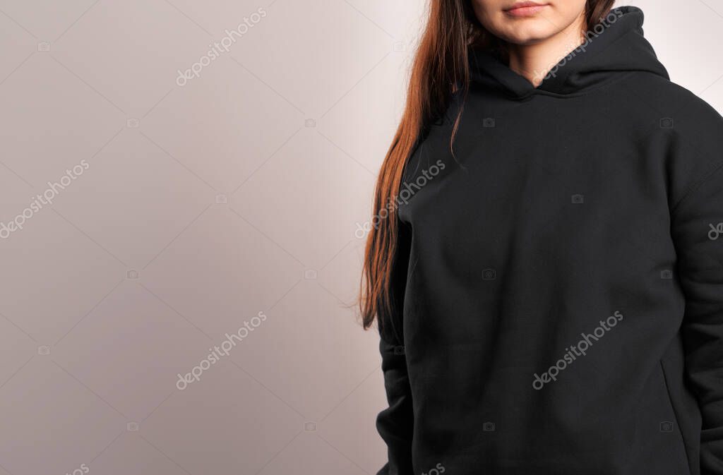 Woman Showcasing a Black Hoodie for Logo Branding. Streetwear clothing mock-up. Logo on shirt template copy space.