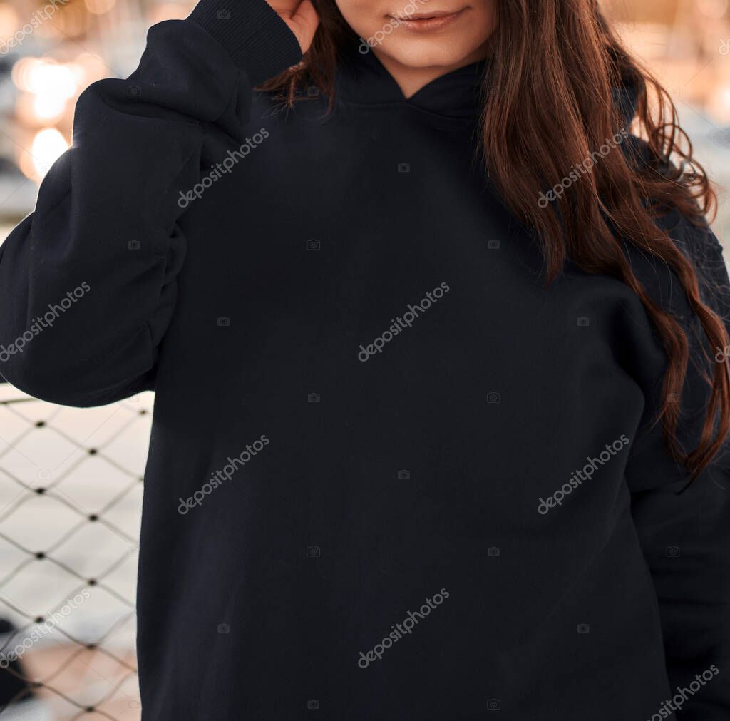 Woman wears a black hoodie mock-up. Streetwear clothing branding. Logo on shirt template copy space.