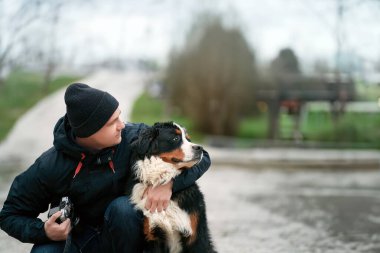 Mutlu sahibi ve genç Bernese köpeği. Sevimli Bernese Dağ Köpeği ve İsviçre Alplerinde Bir Erkek Portresi