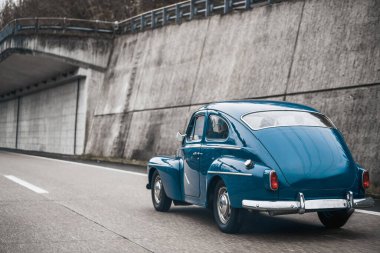 Halka açık otoyolda eski bir Avrupalı araba modeli. Mavi eski model Coupe yolda hız yapıyor..