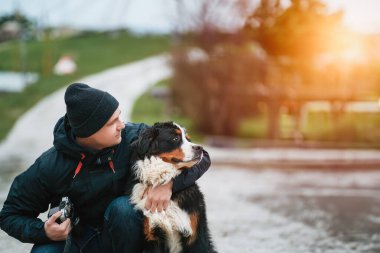 Neşeli Bernese Dağ Köpeği ve İsviçre Alplerinde Mutlu Sahibi Portresi. Mutlu erkek ve genç köpekle neşeli bir bağ..