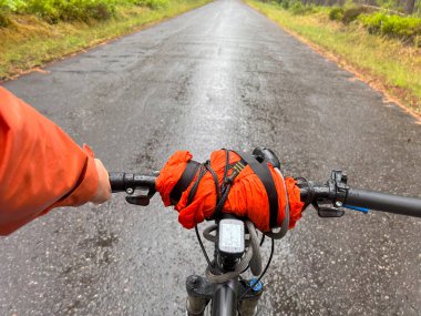 Bisiklet yaz gezisi. Dışarıyı kucaklayan bir bisikletçinin ilk insan görüntüsü. Bisiklet gidonunu tek elle tutmak. Yaz zamanı açık hava sporu aktivitesi. Birinci şahıs manzaralı bisiklet sürmek