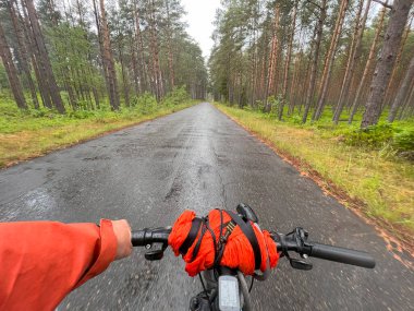 Bisiklet gidonunu tek elle tutmak. Yazın açık hava sporu aktivitesi kavramı. Bisiklet sürmenin birinci şahıs görüntüsü.