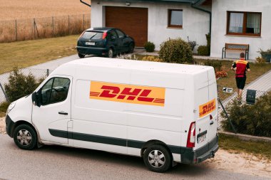 12.07.2023. Polonya, Avrupa. Verimli DHL Teslimatı. Iconic Yellow Van Banliyö Polonya 'ya paket getiriyor. DHL' den (Deutsche Post International) bir paket teslimat minibüsü Avrupa 'da bir kasabada park halinde..