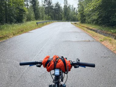Bisiklet yaz gezisi. Dışarıyı kucaklayan bir bisikletçinin ilk insan görüntüsü. Bisiklet gidonunu tek elle tutmak. Yaz zamanı açık hava sporu aktivitesi. Birinci şahıs manzaralı bisiklet sürmek