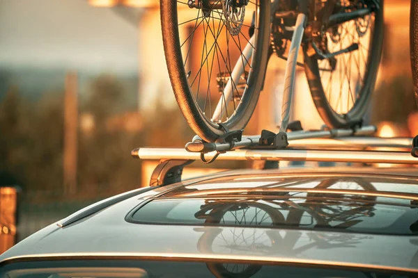 Transportation of bicycles on the roof of the car. Concept of a summer trip on a car trip with a bike. Sports equipment transportation.