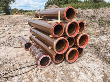 İnşaat alanında kullanılan büyük kahverengi boruların arka planı. Yerde bir sürü büyük boru var. Lağım inşaatı devam ediyor. boru arkaplanı