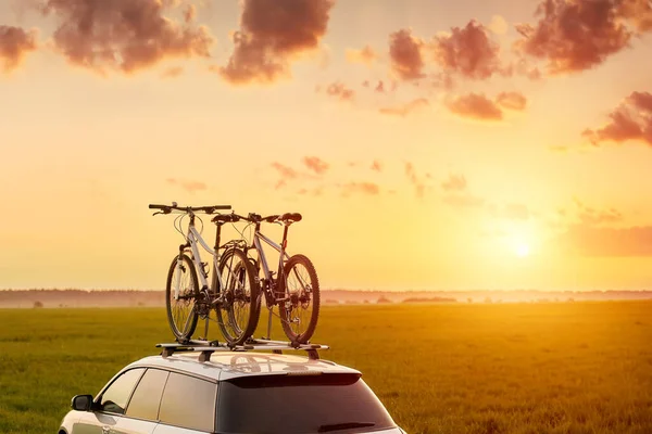 Transportation of bicycles on the roof of the car. Concept of a summer trip on a car trip with a bike. Sports equipment transportation.