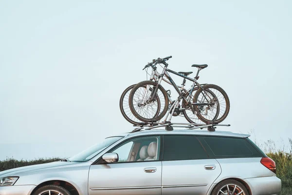 Outdoor Adventure Awaits. Family Car with Bicycles Mounted on Roof Rack. A vehicle with top mounted bikes.