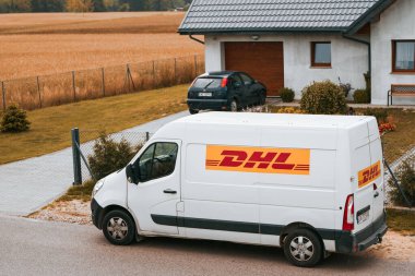 12.07.2023. Polonya, Avrupa. Verimli DHL Teslimatı. Iconic Yellow Van Banliyö Polonya 'ya paket getiriyor. DHL' den (Deutsche Post International) bir paket teslimat minibüsü Avrupa 'da bir kasabada park halinde..