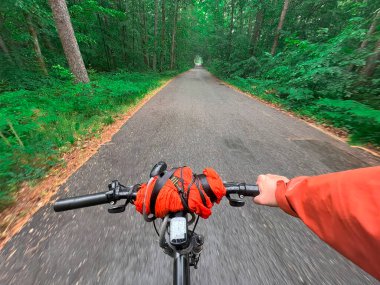 Bisiklet gidonunu tek elle tutmak. Yazın açık hava sporu aktivitesi kavramı. Bisiklet sürmenin birinci şahıs görüntüsü.