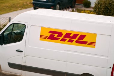 12.07.2023. Polonya, Avrupa. Verimli DHL Teslimatı. Iconic Yellow Van Banliyö Polonya 'ya paket getiriyor. DHL' den (Deutsche Post International) bir paket teslimat minibüsü Avrupa 'da bir kasabada park halinde..