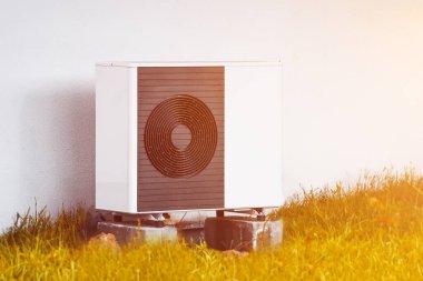 Çimlerin arasındaki evin dışındaki bir havalandırma ünitesi. Modern HVAC ve ısı pompa sistemi