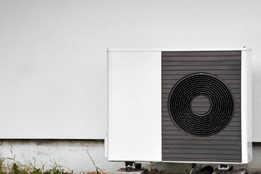 Çimlerin arasındaki evin dışındaki bir havalandırma ünitesi. Modern HVAC ve ısı pompa sistemi