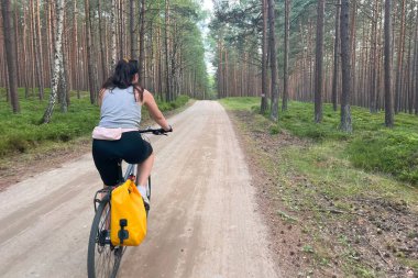 Kırsalda bisiklet süren genç bir kadının arka görüntüsü. Bisikletle seyahat etmek. açık hava aktivitesi.