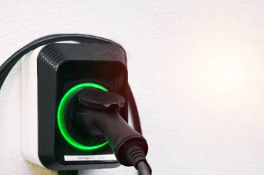 EV şarj aletinin priz tutucusu. Beyaz Saray duvarına monte edilmiş duvardaki kablo ile şarj istasyonu. Sürdürülebilir gelecek konsepti. Elektrikli arabalar..