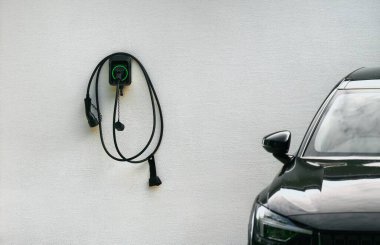 EV şarj aletinin priz tutucusu. Beyaz Saray duvarına monte edilmiş duvardaki kablo ile şarj istasyonu. Sürdürülebilir gelecek konsepti. Elektrikli arabalar..