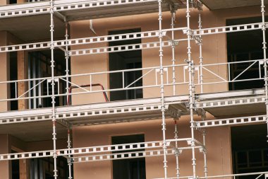 Enerji tasarruflu bir apartman inşa ediyorum. Bir evin iskelesi var. İnşaat halindeki iskeleli yüksek bir bina. Emlak piyasasına yatırım. Yeni Bina İnşaat Alanı.