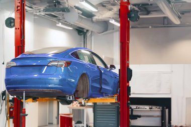 Modern bir araba servisinde elektrikli taşıt bakımı. Profesyonel bir atölyede elektrikli araç bakımı. EV nakil aracı tamir ediliyor.