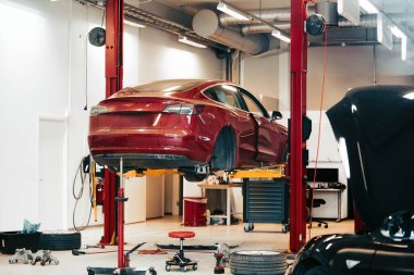 Modern bir araba servisinde elektrikli taşıt bakımı. Profesyonel bir atölyede elektrikli araç bakımı. EV nakil aracı tamir ediliyor.