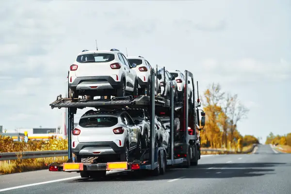 Tow truck with a cars on the highway road. Tow truck transporting car on the autobahn. Car service transportation concept. Roadside Rescue.