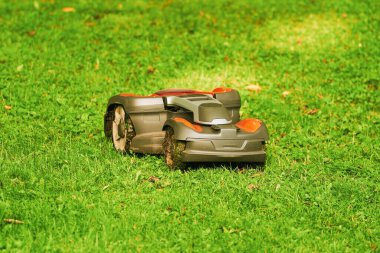 Çimlerin üzerinde robot çim biçme makinesi, yan görüş. Otomatik çim biçme makinesini kapatın. Akıllı çim bakımı. Elektronik çim biçme makinesi.