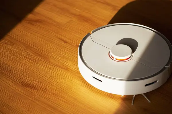 Vacuum cleaner cleans the floor. Robotic vacuum cleaner is on a laminate wooden floor. Smart home, housework, cleaning technology concept. Copy space. Smart Home Cleaning.