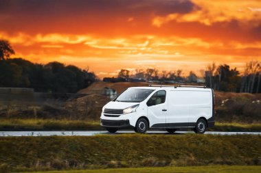 Şehir Otobanı 'nda hızlı hareket eden beyaz minibüs. Dağıtım ve Lojistik faaliyette. Modern Teslimat Minibüsü yolda. Nakliye ve dağıtım konsepti.