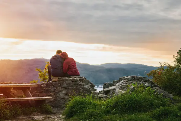 Capturing the Sunset Moment on an Outdoor Adventure. Portrait of a couple from behind. outdoors adventures of friends and couple. Man and woman watching beautiful sunset after hiking. Hiking Together.
