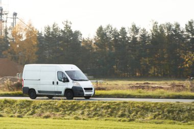 Şehir Otobanı 'nda hızlı hareket eden beyaz minibüs. Dağıtım ve Lojistik faaliyette. Modern Teslimat Minibüsü yolda. Nakliye ve dağıtım konsepti.