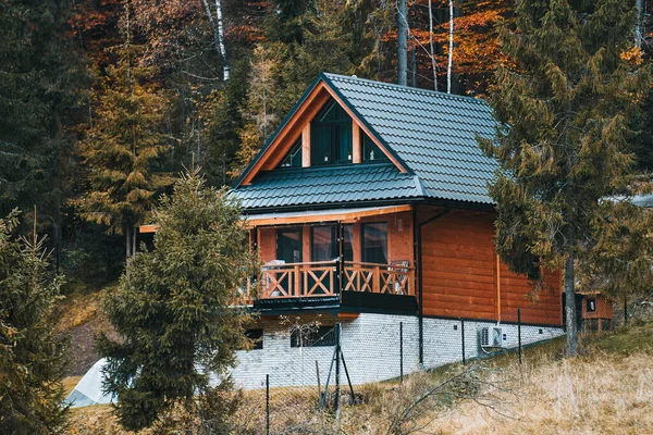 Güzel doğada ahşap bir ev. Dağ tarzı ev. Renkli yaprakları ve dağları olan ağaçlarla çevrili modern ahşap evlerle dolu güzel bir manzara. Ormanda bir dağ evi..