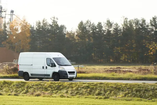 Fast-Moving White Delivery Van on Urban Highway. Distribution and Logistics in Action. Modern Delivery Van on the Road. Shipping and distribution concept.
