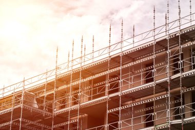 Enerji tasarruflu bir apartman inşa ediyorum. Bir evin iskelesi var. İnşaat halindeki iskeleli yüksek bir bina. Emlak piyasasına yatırım. Yeni Bina İnşaat Alanı.