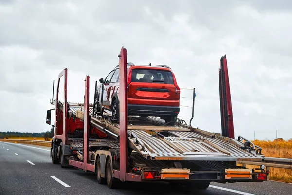 A tow truck carries a car on a flatbed trailer on the highway, providing transport service and assistance after an accident.