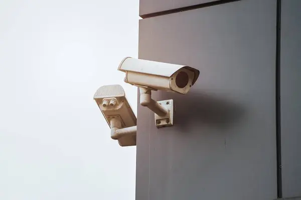 Outdoor security camera with a waterproof cover is installed on the exterior of a modern house, as part of a home security system concept that uses ip cctv technology. Video surveillance and control.