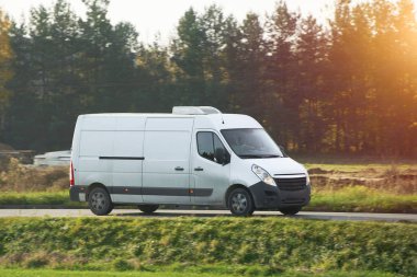 Beyaz, modern kargo kargo kargo aracının şehir ve şehir banliyölerine giden otoyolda hızla ilerleyişinin flaş görüntüsü. Otoyolda küçük bir otobüs yolculuğu. Dağıtım ve lojistik işleri