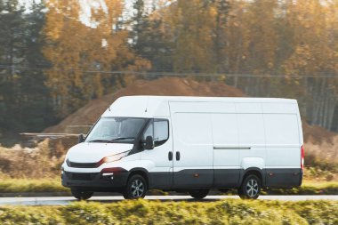 Beyaz, modern kargo kargo kargo aracının şehir ve şehir banliyölerine giden otoyolda hızla ilerleyişinin flaş görüntüsü. Otoyolda küçük bir otobüs yolculuğu. Dağıtım ve lojistik işleri