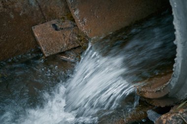 Atık su ve kanalizasyon bir borudan kirli bir nehre akar, kötü bir koku ve kimyasal tehlike yaratır. Fotoğraf endüstriyel atıklar ve kötü drenaj sisteminin çevresel etkilerini gösteriyor..