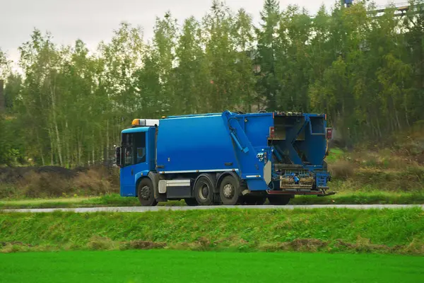 A recycling truck collects garbage bins on a suburban road. The vehicle provides a valuable service for the environment and city. Ecological and save the earth concept. Trash and garbage separation.