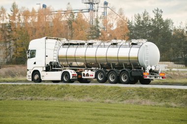 Propan tankıyla yarı kamyonla tehlikeli mal taşımacılığı. Tankın yan görüntüsü var ve yüksek sıcaklıkta sıvı ve çeşitli tehlikeler için tehlikeli etiketler gösteriyor. Kamyon ADR 'yi izliyor.