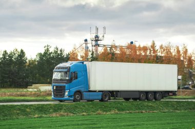Bir yük kamyonu bir konteynırı otoyolda taşır. Avrupa konseptinde lojistik. Arkasında güzel kırmızı bir güneş batarken bir otoyolda kargo kamyonu sürüyorum..