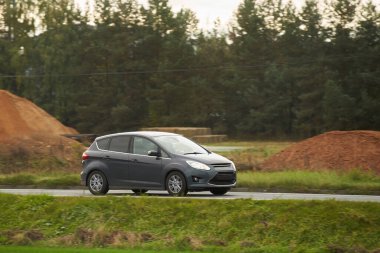 Kırsalda araba hız yapıyor. Modern bir hatchback 'in içinde yeşilliklerle çevrili bir yolda hızlı sürüyorum. Otoyolda ilerleyen modern hatchback 'in yan görüntüsü.