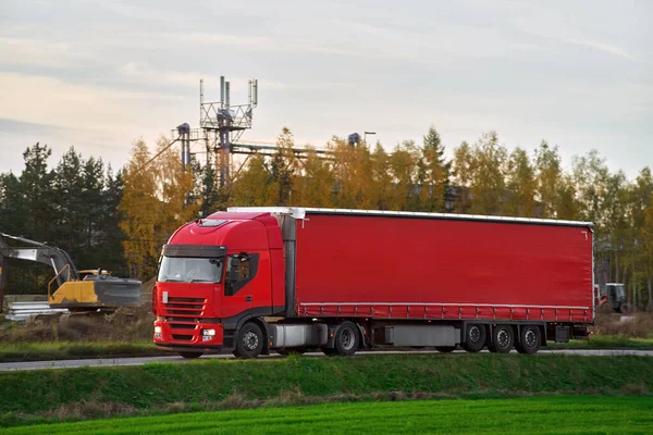 A freight truck transports a container on a motorway. Logistic in Europe concept. Driving a cargo semi-truck on a highway with a beautiful red sun setting behind.