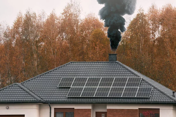 dark cloud of smoke from a chimney pollutes the winter sky over a house