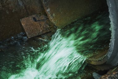 Bir kanalizasyon borusu zehirli atık suyu bir nehre boşaltarak çevresel kirliliğe ve ekolojik hasara yol açar..