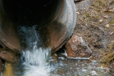 Bir kanalizasyon borusu zehirli atık suyu bir nehre boşaltarak çevresel kirliliğe ve ekolojik hasara yol açar..