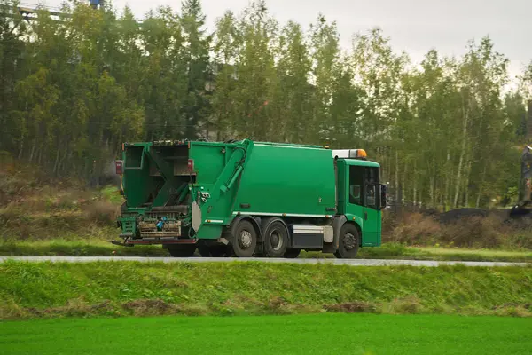 Recycling truck rides on the road in the suburbs. Garbage pickup truck. Concept of sorting garbage for a better sustainable future.