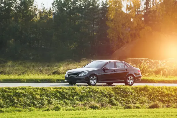 Günbatımı ve orman geçmişi olan lüks spor bir arabada hız yapmak. Entellektüel pahalı araba yolda. Otobanda lüks ve lüks bir araba var..