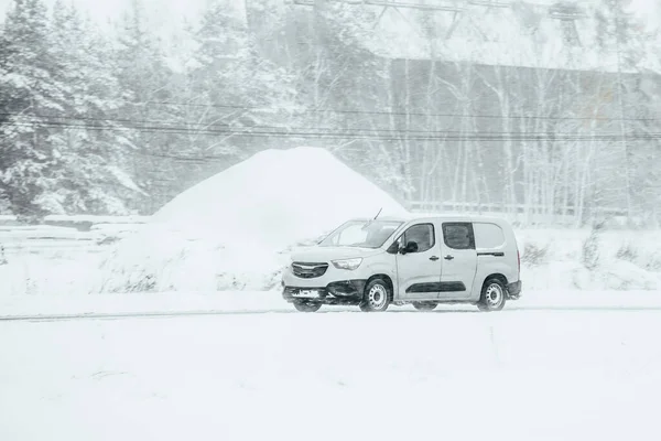 Van driving in the snow. Logistics on a snowy winter day. Delay of cargo delivery due to snowfall in winter. Side view of a commercial cargo van.