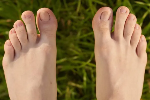 A man bare foot on green grass. A top view of a human leg and toes on a white background. A closeup of natural skin and wellness.